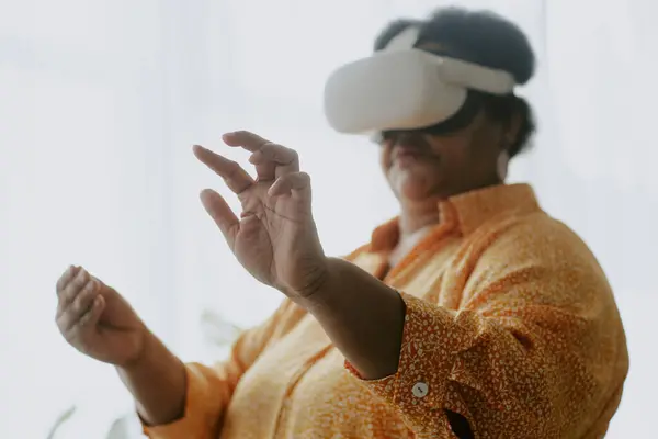 stock image Medium close up photo of senior African American woman imagining her touching things in air using VR headset