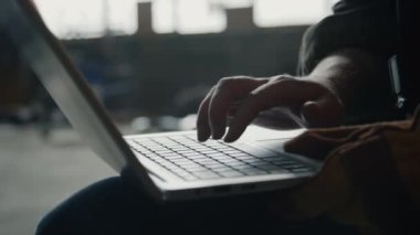 Endüstriyel fabrikada çalışırken laptopta yazan tanınmayan işçilerin yakın çekim görüntüleri.