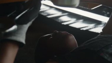 Siyah kadın fabrika işçisi traktörün altında yatıyor ve İngiliz anahtarıyla parçaları onarıyor.