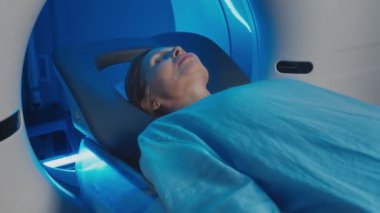 Klinikteki tanısal görüntüleme işleminden sonra MRI tarayıcısından çıkan orta yaşlı beyaz kadının orta yavaş çekimi.