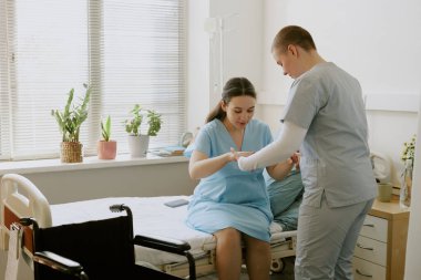 Genç hemşire, hamile hastaya kasılmalar sırasında ayağa kalkmasında yardım ediyor.