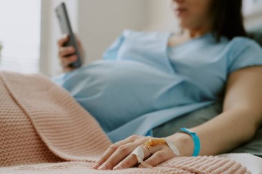 Orta boy bir kadın eli, parmağında altın bir alyans, diğer elinde de akıllı telefon.