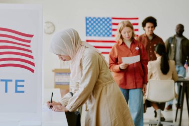 Seçim günü sandık merkezinde oy pusulasında aday için tesettürlü genç Müslüman kadın