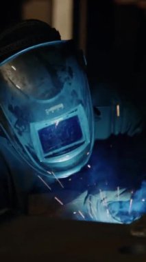 Endüstriyel fabrikada koruyucu iş giysisi ve maske demiri kaynakçısının dikey görüntüsü