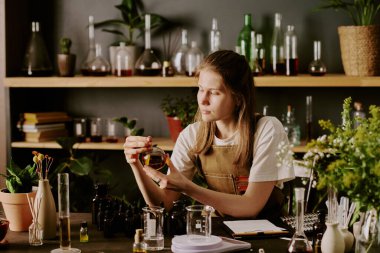 Genç bayan parfümcü ev yapımı parfüm örneklerini beğeniyor.