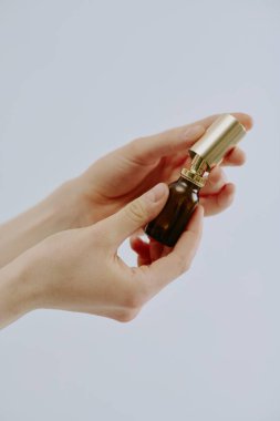 Manikürlü kadın elleri cam şişede yepyeni bir parfüm taşıyor.