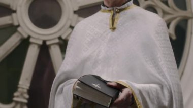 Beyaz şezlonglu, İncil 'i kapatan ve Katedral' de kameraya poz veren kıdemli papazın görüntüsünü kaldır.