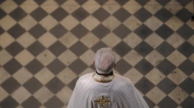Katedraldeki sıralarda yürürken gri saçlı rahibin yukarıdan görünüşü