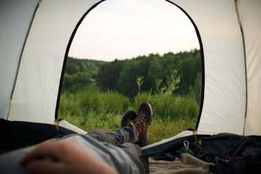 Tanımlanamayan erkek turistin yaz akşamları çadırda dinlenen görüntüsü.