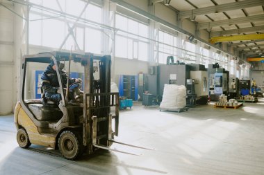Tanımlanamayan fabrika işçisi forklift kullanıyor.
