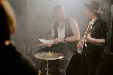 İki olgun ve genç rock müzisyeni performans için hazırlanırken konuşuyor.