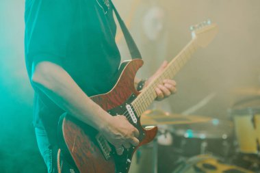 Sahnede elektro gitar çalan siyah tişörtlü, tanınmayan bir adamın orta boy fotoğrafı.