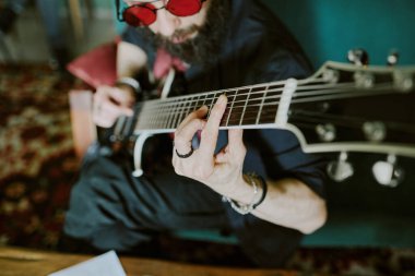 Kırmızı gözlüklü, elektro gitar çalan sakallı rock müzisyeninin yüksek açılı görüntüsü
