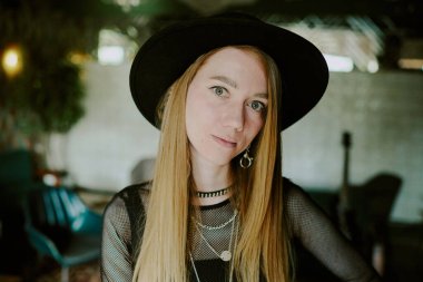 Kafkas kökenli, uzun saçlı, şapkalı genç bir rock müzisyeninin Cmaera 'ya bakışları.