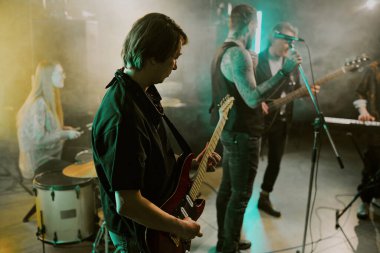 Erkek müzisyenin gece kulübünde rock grubuyla elektro gitar çalarken seçici odak noktası.