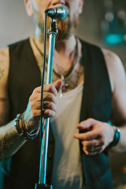 Sahnede mikrofon tutan tanınmayan heavy metal şarkıcısının dikey odak çekimi.