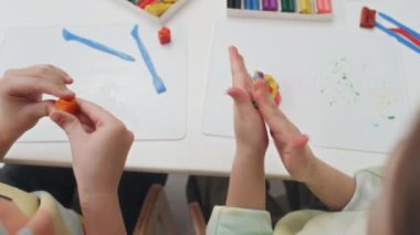Tanımlanamayan anaokulu öğrencilerinin sanat dersi sırasında ellerindeki küçük oyun hamurlarını yuvarlayarak ve yoğurarak modelleme kilini kullanmayı öğrenmelerinin en üst görüntüsü
