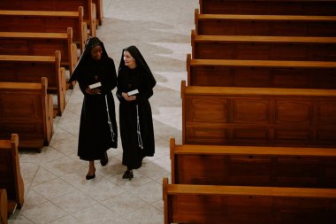 İki Kafkas ve Siyahi Katolik rahibenin dua kitaplarını tutarken, saflık içinde yürürken ve konuşurken yüksek açılı görüntüsü.