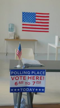 Dikey olarak hiç kimse seçim müfettişinin masasından kağıt oylar, Amerikan bayrağı ve açık oy kullanma merkezini gösteren tabelalarla vurulmadı.