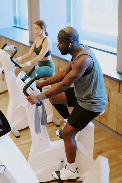 stock image High angle shot of gym visitors warming up in cardio zone of premium fitness club, they doing cardio on exercise bike