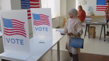 Genç müslüman kadın, seçim günü oy verirken kabinde oy kullanırken başörtüsü takıyor.