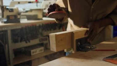 Afrika kökenli Amerikalı marangozun ahşap zımparaladığı ve ahşap atölyesinde talaş uçurduğu yakın plan.