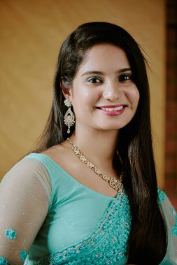 Açık renk makyaj ve turkuaz elbise giymiş genç ve güzel bir kadın modelin portresi kameraya bakarken geniş bir gülümseme.