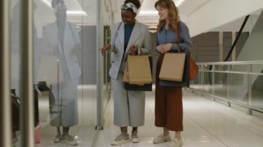 AVM 'de lüks bir mağazada sergilenen son moda mücevherlere bakan Kafkasyalı bir bayan arkadaşla tam bir Afrikalı Amerikalı kadın fotoğrafı.