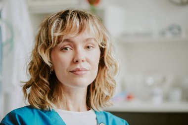 Genç beyaz bir hemşirenin portresi doğrudan kameraya bakıyor ve gülümsüyor.