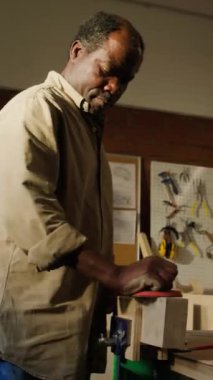 Marangozluk atölyesinde çalışırken zımpara zımparasıyla ahşap zımparalarken çekilmiş dikey bir fotoğraf.