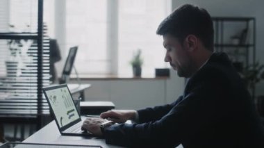 Bilgisayarda finansal verilerle çalışan ve ofisteki masada notlar alan işadamının yan görüntüsü, telefonda konuşan iş kadını
