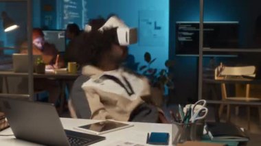 Afrika kökenli Amerikalı erkek bilişim teknisyeninin iş yerinde iş arkadaşlarıyla birlikte oturup sanal gerçeklik uygulamasını test ederken çekilmiş zaman çizelgesi.