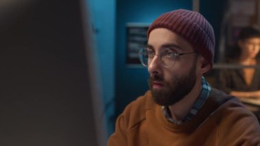 Bilgi işlem ofisinde çalışan ve yazılım sorunlarını çözerek kullanıcılara uzaktan teknik destek sağlayan genç beyaz adamın yüzünün yakın çekimi