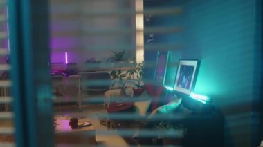 Çok renkli neon ışıklı modern ev kayıt stüdyosunun kör penceresinden bakın. Kanepede çalışma istasyonu, vinil çalar ve gitar var.