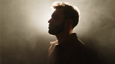 Genç erkek vokalist sisli sahnede arka planda duruyor ve canlı müzik performansı sırasında ifade ile şarkı söylüyor.