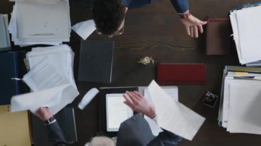 İki iş ortağının tam üstünde, kızgın yönetici çalışanının önünde belgeleri yırtıyor.