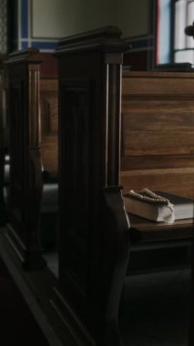 Boş kilisedeki ahşap sıralarda İncil ve tespih çekimleri.