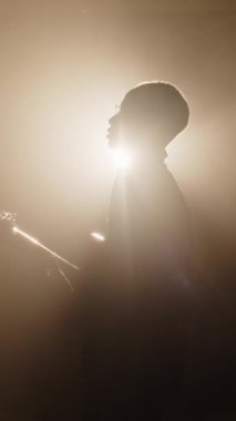 Sahnede canlı performans sergilerken gitar çalan ve şarkı söyleyen siyah gitaristin dikey zoom çekimi