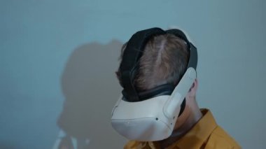 VR kulaklık takarak heyecan verici sanal gerçeklik oyunu oynayan, silah seslerinin gerçekçi seslerini deneyimleyen, tanınamayan bir gencin orta boy yakın çekimi.