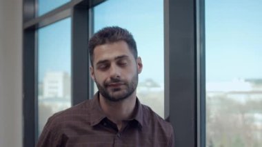 Genç beyaz erkek okul müdürünün portresi. Kendine güveni tam, pencereye yaslanmış kameraya bakıyor.