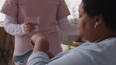 Siyahi yaşlı bir kadının elinde bastonla oturup hapları ağzına koyduğunu, tanınmayan hemşirelerden bir bardak su içtiğini ve onunla birlikte tablet içtiğini düşünün.