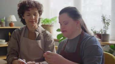 Down sendromlu bir kız yumurta kırıyor ve cam kaseye döküyor. Yemek kursunda bayan öğretmen onu övüyordu.