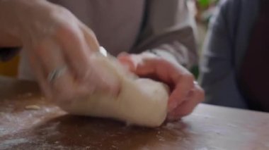 Mutfak masasında hamuru yoğurup buğday döşemesi ekleyen tanınmayan bir kadının elleri yakın plan görüntüsü.