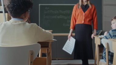 Küçük Afro-Amerikan çocuğun masada oturup, bayan öğretmen sorusunu dinlerken ve ilkokulda müzik dersi sırasında elini kaldırırken çekilen görüntüler.