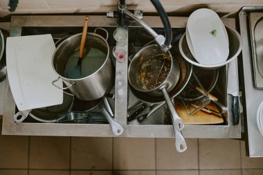 Çelik mutfak lavabosundan arta kalan kirli çanak çömlek manzarası