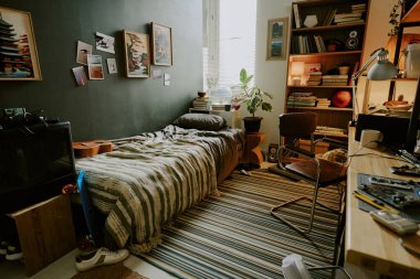 Yatakhanedeki dağınık erkek odası mobilya ve kişisel eşyalarla dolu.