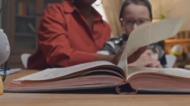 Afrika kökenli Amerikalı annenin, evlat edindiği beyaz anaokulu çocuğu, babası ve diğer çocuğuyla birlikte kitap sayfasını çevirirken yakın plan çekimleri.