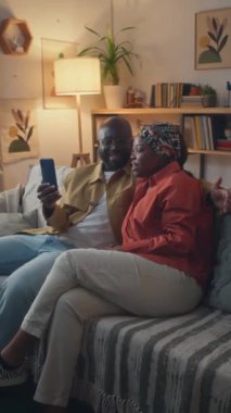 Siyahi evli çiftin evdeki kanepede otururken arkadaşlarıyla telefon görüşmelerini dikey çekiyoruz.