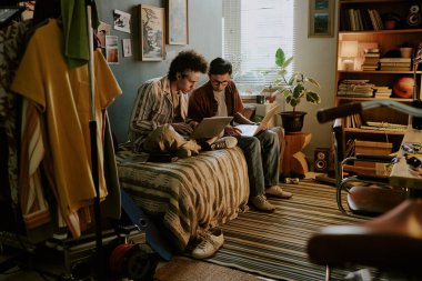 Üniversite öğrencileri yataklarında oturup farklı veritabanlarını karşılaştırırken aynı zamanda dağınık yurt odalarında birlikte çalışıyorlar.