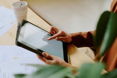 Yüksek açılı görünüm, dijital tabletin içeriğini boş ekran ile kaydıran tanınmayan iş kadınının elleri